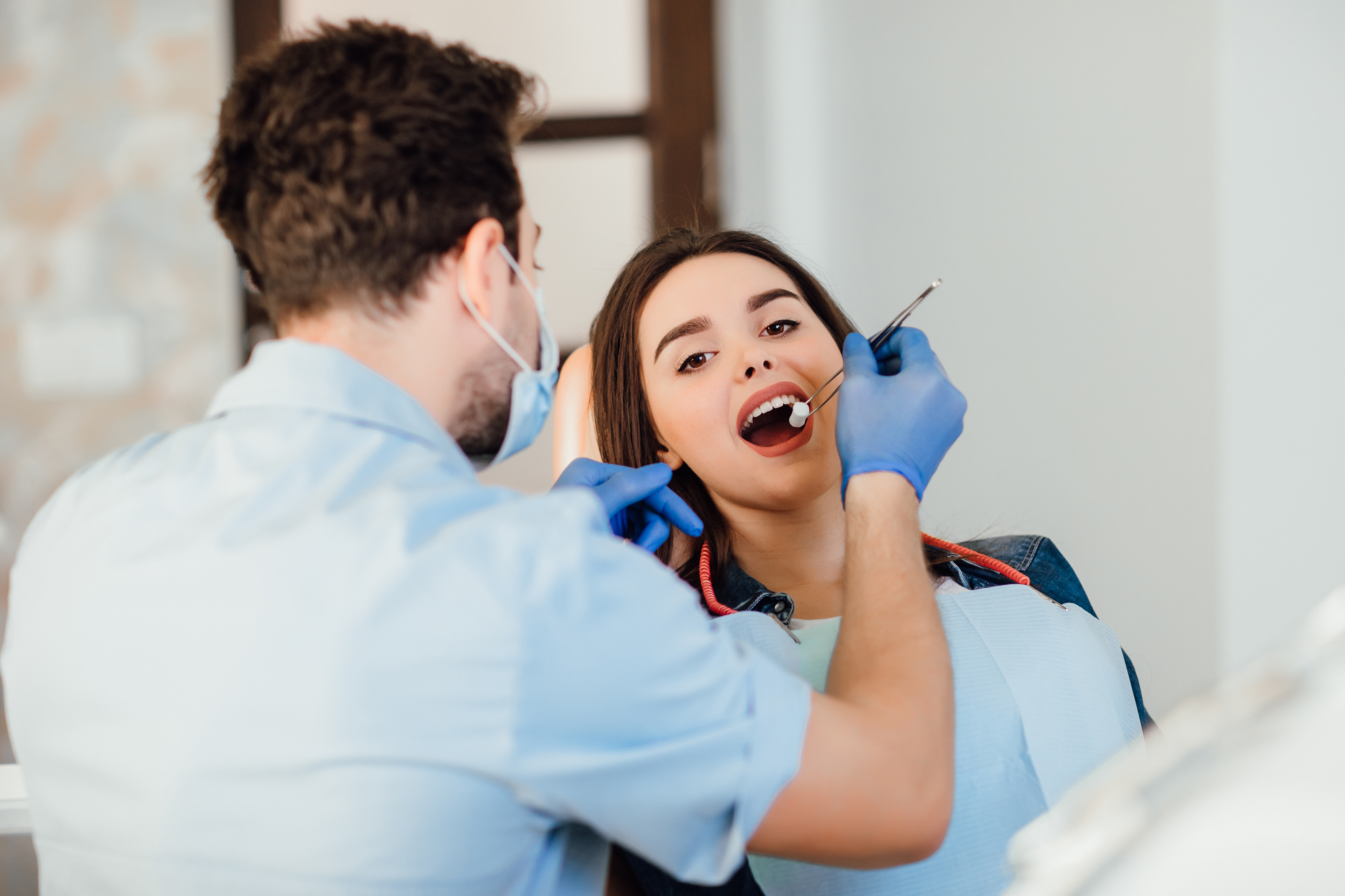 dentist-making-professional-teeth-cleaning-withb-the-cotton-female-young-patient-at-the-dental-office